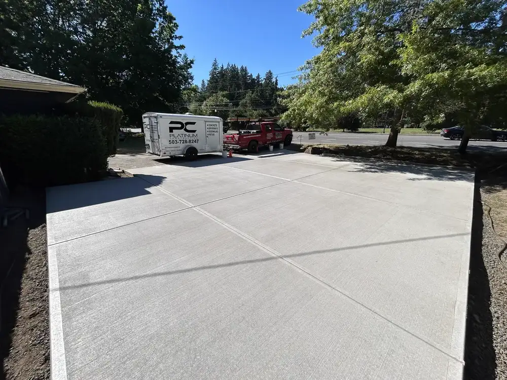 Platinum Construction LLC work trailer and truck on a completed residential concrete driveway project in Portland, OR